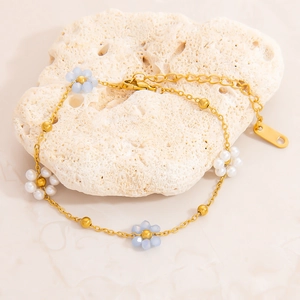 Macro détaillée du bracelet plaqué or 18K avec fleurs bleu clair et perles dorées