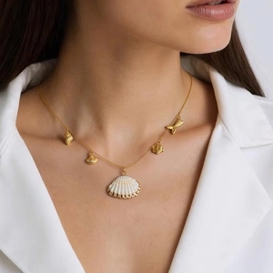 Collier marin avec pendentifs dorés en forme de queue de poisson et coquillage sur mannequin