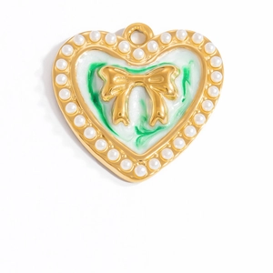 Dettaglio macro del ciondolo a cuore in smalto verde con perle e fiocco dorato