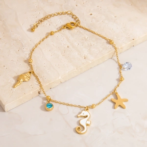 Detail of 18K gold anklet with starfish, seahorse pendants and blue cubic zirconia charms