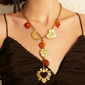 Vintage gold Y-necklace with amber heart, moon pendant and sunburst charm on a model