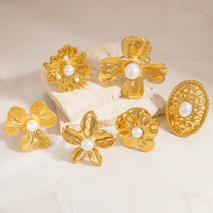 Close-up of 18K gold plated rings with floral patterns and white pearl inlay detail