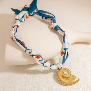Detailed macro view of 18K gold conch pendant with pearl on colorful silk ribbon necklace