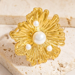 Elegant 18K gold-plated flower ring with pearls on a beige stone surface