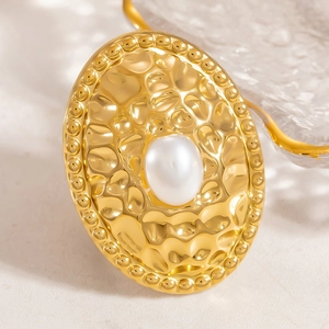 Elegant 18K gold hammered oval stud earring with central pearl on stone surface