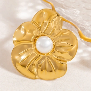 Detailed macro of gold flower brooch with pearl inlay and textured hammered metal petals