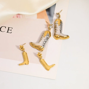 Cowboy boot earrings in gold and silver tones with star accents on satin background