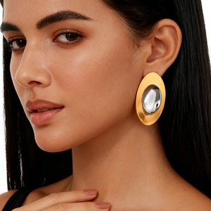 Dettaglio della modella che indossa grandi orecchini ovali bicolore oro e argento opaco