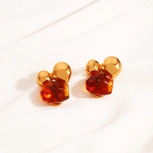 Macro detail of amber resin and gold irregular metal earring on white fabric