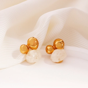 Detailed macro view of 18K gold earrings with textured resin stones on white fabric