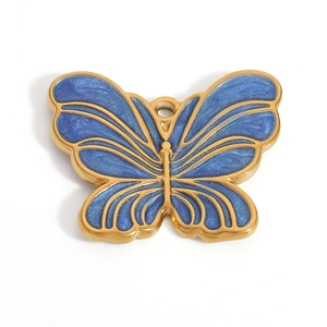 Macro shot of gold butterfly charm with blue shimmering enamel inlay for jewelry DIY