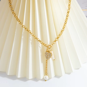 Gros plan sur pendentif cœur doré serti de cristaux avec perles blanches élégantes