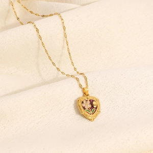 Detail van vintage gouden hartmedaillon met roze emaille bloemen en fijne O-ketting link