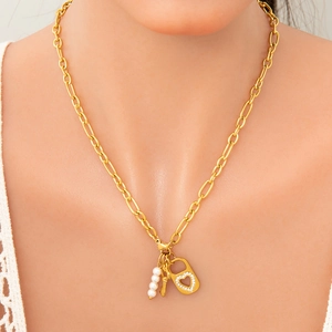 Détail du collier doré avec pendentif cadenas cœur, clé et perles blanches