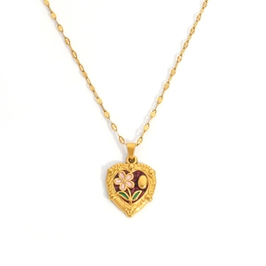Detail van een vintage hart hanger met roze bloemen emaille en gouden reliëfpatroon