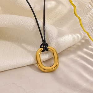 Detail showing polished gold geometric oval pendant with minimalist black cord necklace