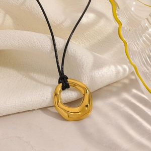 Close-up of irregular geometric gold circle pendant with minimalist black cord necklace