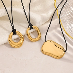 Close-up of three irregular 18K gold-plated pendants with a glossy mirror finish on black cords