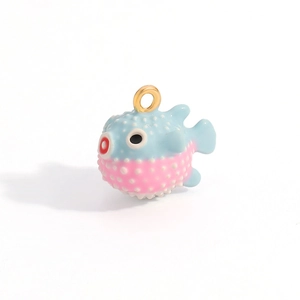 Detailed macro view of light blue and pink puffer fish charm with gold ring attachment