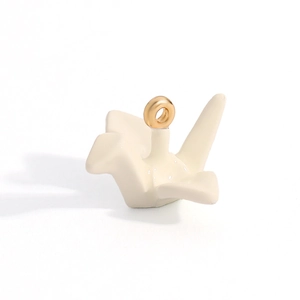 Detailed view of an origami crane jewelry pendant in cream white with a gold ring