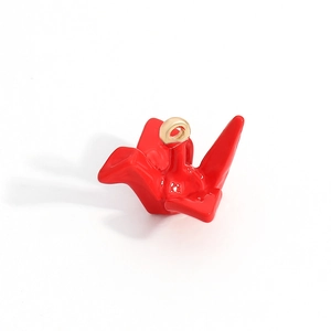 Detail of a shiny red origami crane charm with a gold-tone jump ring for DIY jewelry making