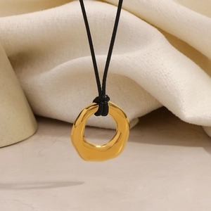 Detail of a minimalist gold 18K plated stainless steel ring pendant on black cord