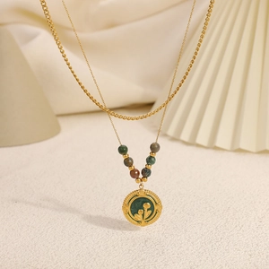 Détail macro du collier double couche en or 18K avec pendentif fleur en émail vert et perles