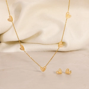 Detailed macro of heart necklace and earrings set with gold plating and white enamel