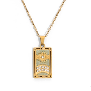 Makroaufnahme von Gold-Tarot-Sonnenanhänger mit grünem Emaille und Zirkonsteinen