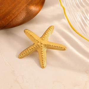 Broche étoile de mer dorée à l'or 18 carats avec texture granuleuse sur marbre