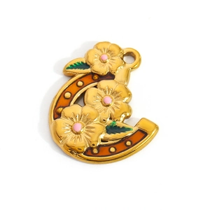 Detailed golden horseshoe pendant featuring floral enamel designs and green leaves