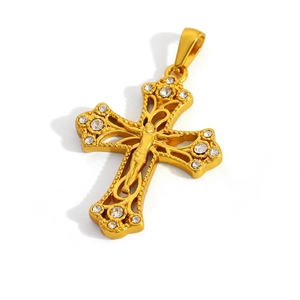 Detailed view of a gold crucifix pendant featuring a relief figure and inlaid crystals