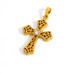 Detailed view of a gold cross pendant with baroque filigree and a central crystal inlay