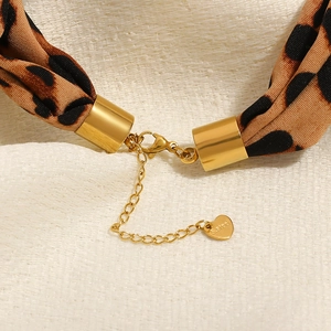 Dettaglio macro della collana a foulard leopardato con ciondolo a cuore in acciaio