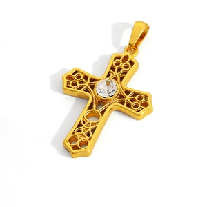 Macro detail of golden stainless steel cross pendant with crystal inlay and hollow patterns