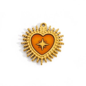 Detail of heart pendant with orange enamel and golden star, stainless steel jewelry piece
