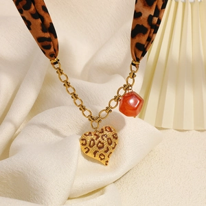Collana foulard in seta leopardata con pendente a cuore in acciaio inox su sfondo beige