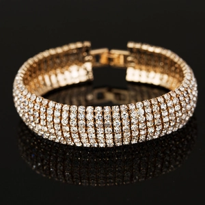 Macro shot of gold five-row rhinestone bracelet with folding clasp on black mirror surface