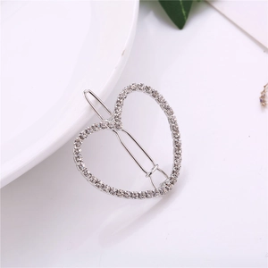 Pince à cheveux coeur argentée scintillante avec strass sur fond blanc minimaliste