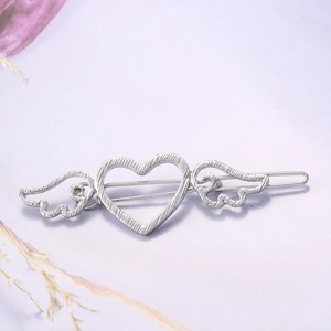 Silver alloy bow hair clip with heart and wings design on a soft purple background