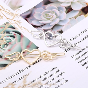 Macro detail of alloy heart wing hair clips in gold and silver with brushed texture