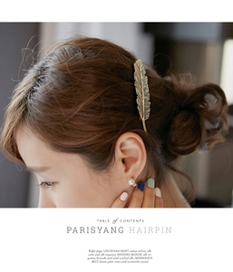 Detailed view of vintage gold feather hair clip in alloy metal on female model hair