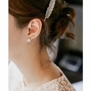Elegant gold leaf alloy hairpin with feather texture shown on a female model
