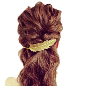 Elegant gold leaf-shaped metal hair clip accessory worn on long wavy hair