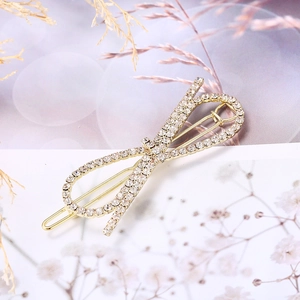 Pince à cheveux élégante en forme de nœud doré avec strass sur fond décoratif fleuri