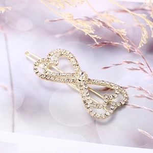 Elegante pasador dorado con corazones entrelazados y diamantes de imitación sobre fondo gris