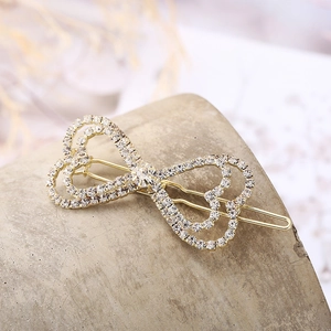 Elegante pinza para el pelo con corazón hueco dorado y brillantes cristales en un soporte