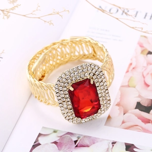 Bracciale rigido dorato traforato con grande pietra preziosa rossa e piccoli cristalli