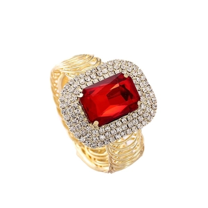 Anello di lusso dorato con grande pietra rossa rettangolare e alone di cristalli