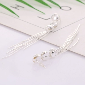 Boucles d'oreilles argentées à trois disques et longues franges sur carte blanche
